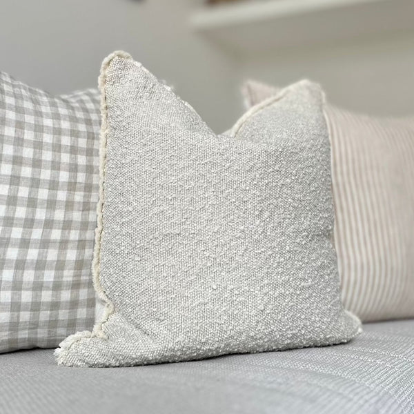 square cream boucle cushion with a cream frayed edge.