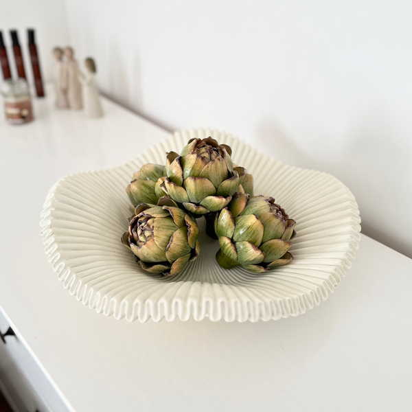 White scalloped edge decorative owl filled with faux green artichoke, sat on a white sideboard