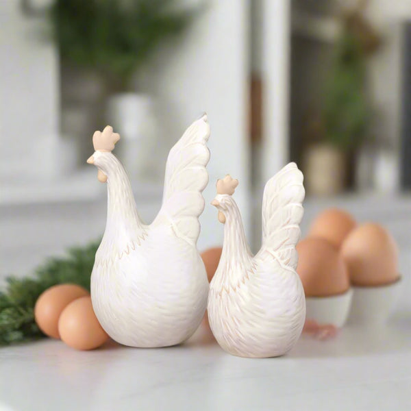 2 Neutral Chicken Ornaments. one large and one small. sat on a kitchen counter in front of eggs