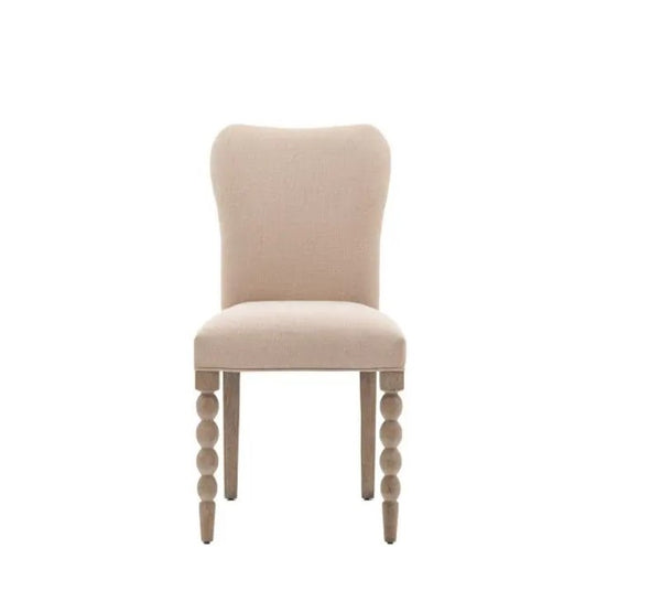 Cream linen fabric dining chair. Front legs are wooden oak coloured round bobble effect. Back legs straight wooden oak effect for stability. Sat on a plain white background for visual contrast