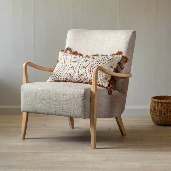 Cream upholstered armchair with oak arms and legs, sat on a wooden floor with a cream back wall