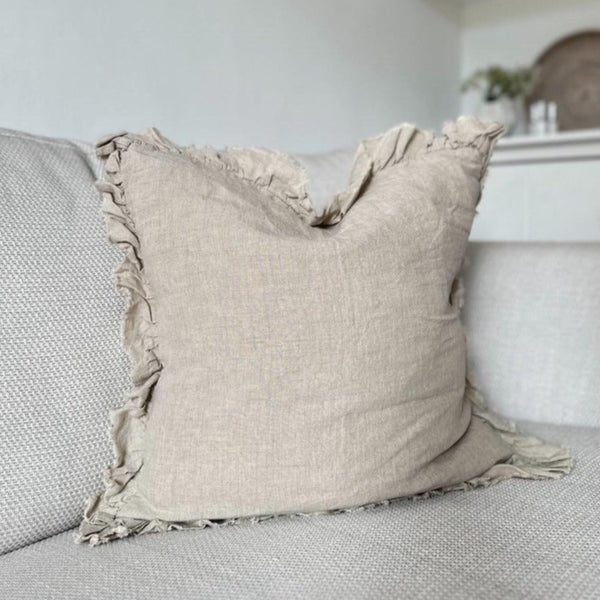 ruffled edge beige linen square cushion on a cream sofa