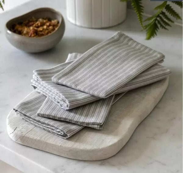 Cream and Grey striped cotton napkins. Folded on a light, wooden chopping board on a kitchen counter for styling.