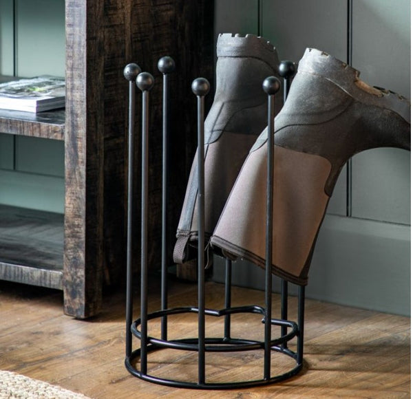 Wyatt Black Iron Boot Stand, with 2 over turned wellies hanging to dry, sat on a wooden floor.